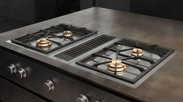 Two gas cooktop modules with brass burners and a grate between them